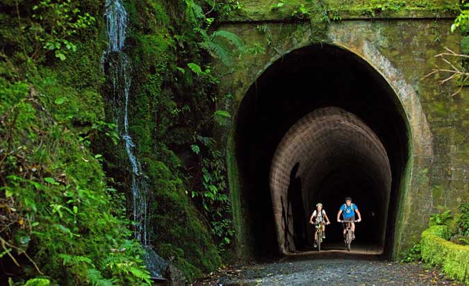 Two cyclists emerging from a tunnel on the Remutaka cycle trail