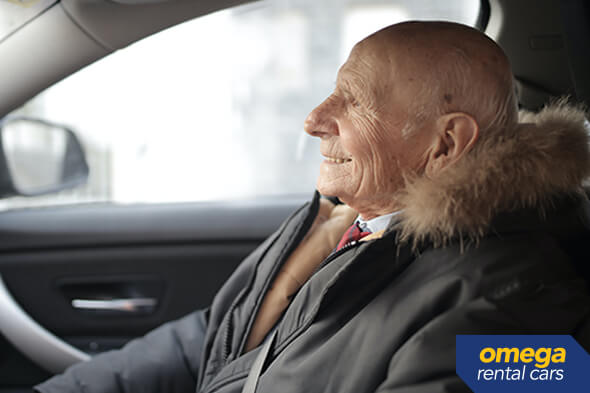 Senior man sitting in a car smiling.