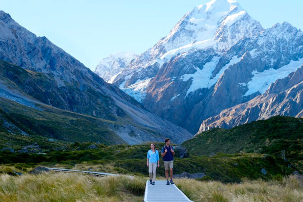Hooker Valley v2 A coupple enjoying a hike in the valley wit snow capped mountains in the background.