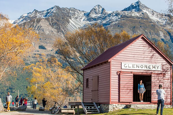 Tourists taking photos infront of the iconic Red Boat Shed at the Glenorchy wharf..