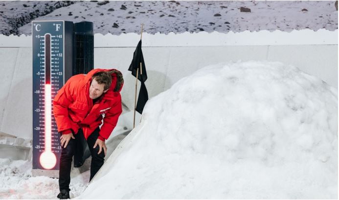 Guide in red jacket in the storm dome with snow hill