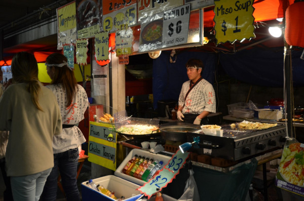 Stallholder standing behind a stall at a food market, ready to serve customers.