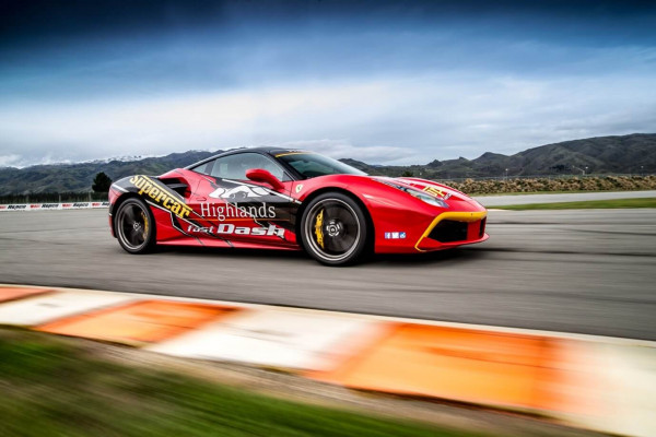 Red racing car doing hot laps around Highland Park raceway circuit.