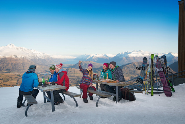 Tourists enjoying the view of Queenstown's snow covered mountains after skiing.