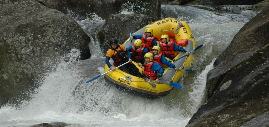 Group of tourists white-water rafting down a rushing waterfall in Rotorua.
