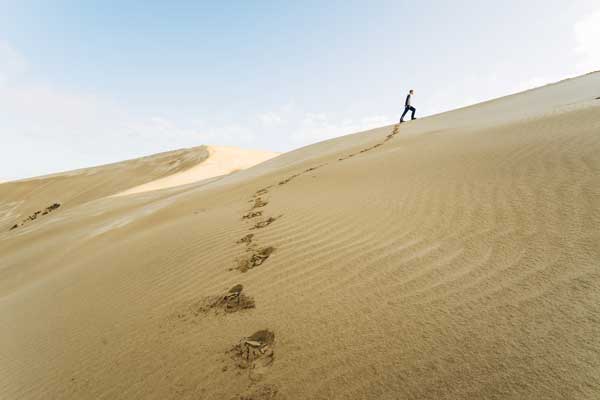 Person walking to the top of the Ahipara Te Paki sand dunes in Northland