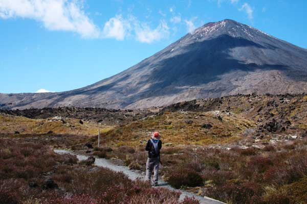 A person hiking across the Tongariro crossing with the mountain in the background